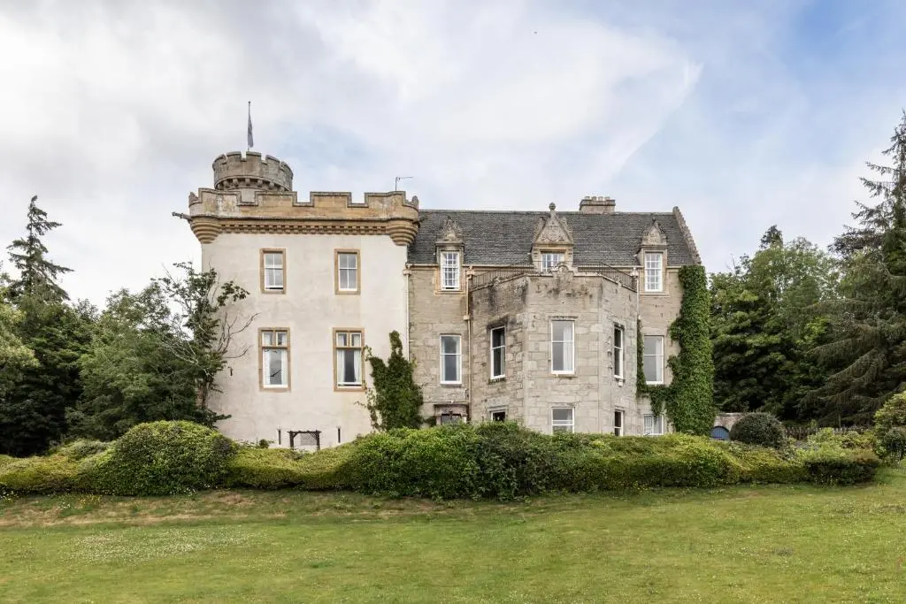 an old castle with a tower on top of a field at Tulloch Castle Hotel \u2018A Bespoke Hotel\u2019 in Dingwall