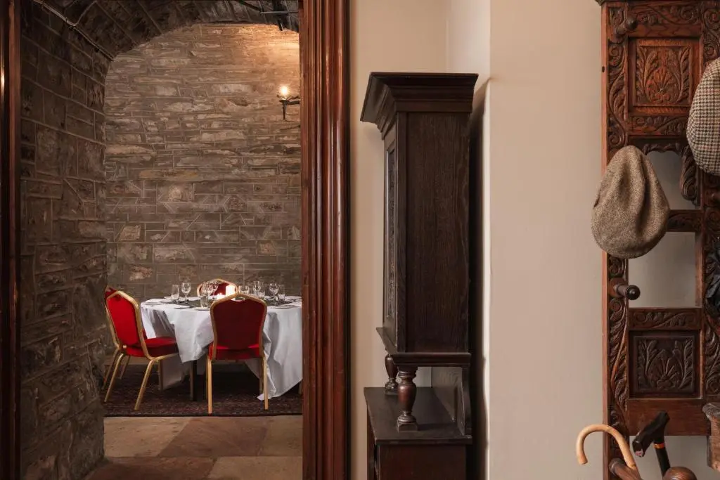 a dining room with a table with red chairs at Tulloch Castle Hotel \u2018A Bespoke Hotel\u2019 in Dingwall
