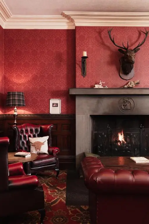 a living room with red walls and a fireplace at Tulloch Castle Hotel \u2018A Bespoke Hotel\u2019 in Dingwall