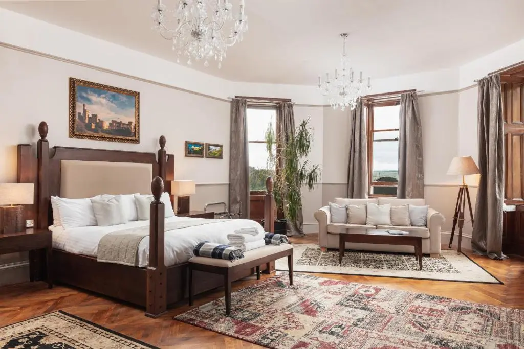 a bedroom with a bed and a couch and a chair at Tulloch Castle Hotel \u2018A Bespoke Hotel\u2019 in Dingwall