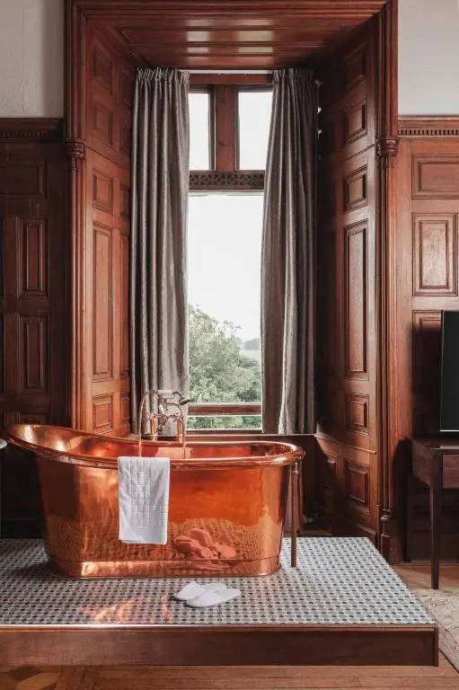 a bath tub in a room with a window at Tulloch Castle Hotel \u2018A Bespoke Hotel\u2019 in Dingwall