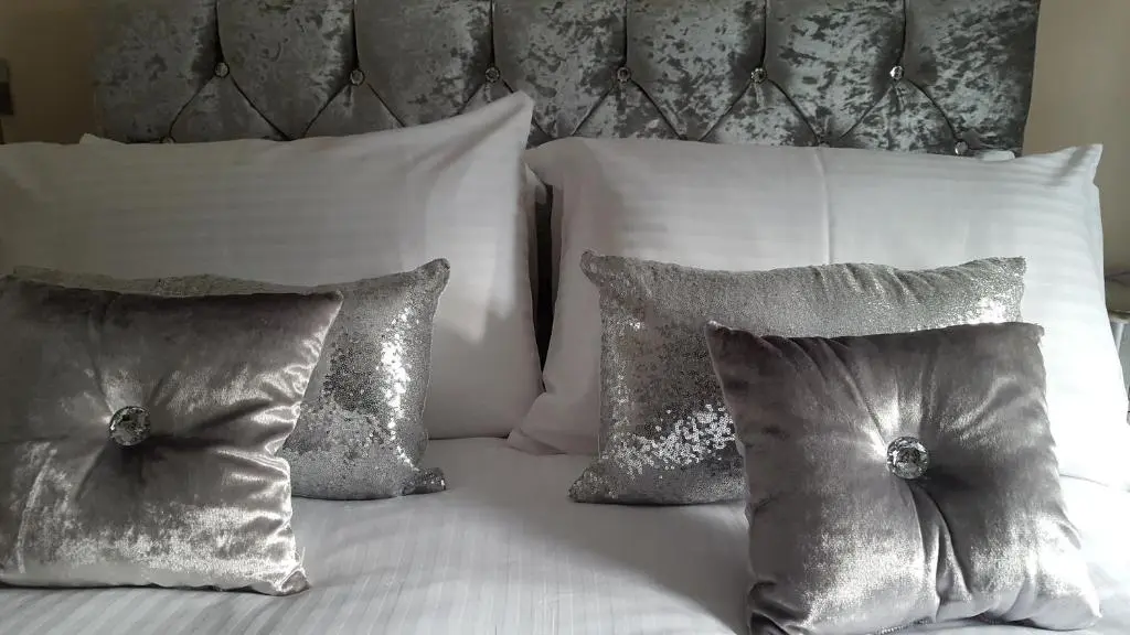 a white bed with four pillows and a headboard at Star Inn Rooms in Ardersier