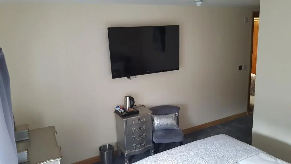 a bedroom with a tv on the wall and a chair at Star Inn Rooms in Ardersier