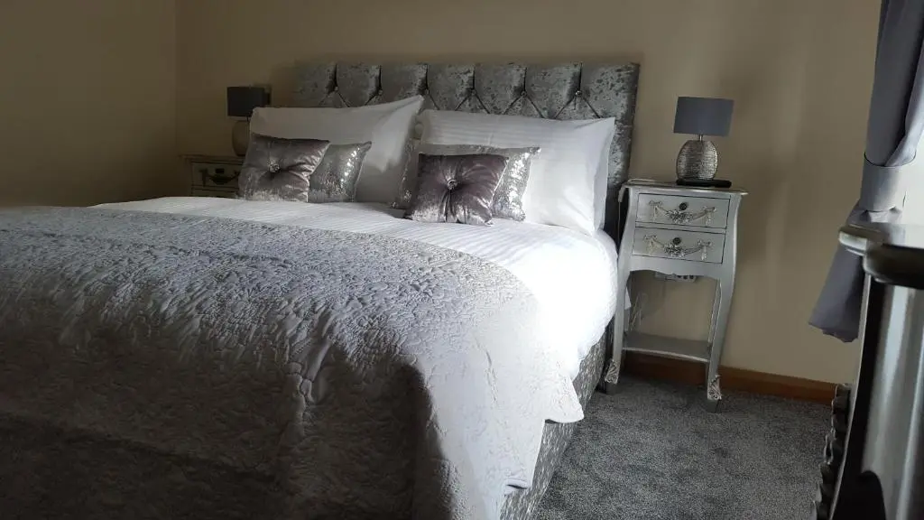 a bedroom with a large bed with white sheets and pillows at Star Inn Rooms in Ardersier