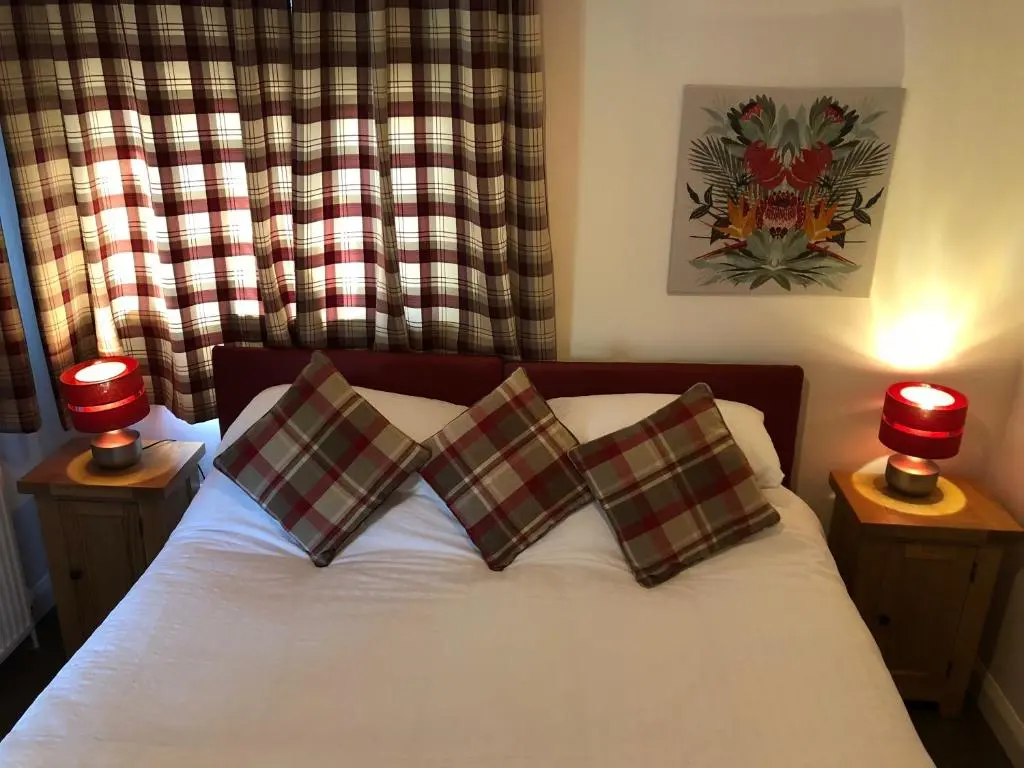a bedroom with a bed with two pillows and two lamps at The Wee Lodge in Inverness