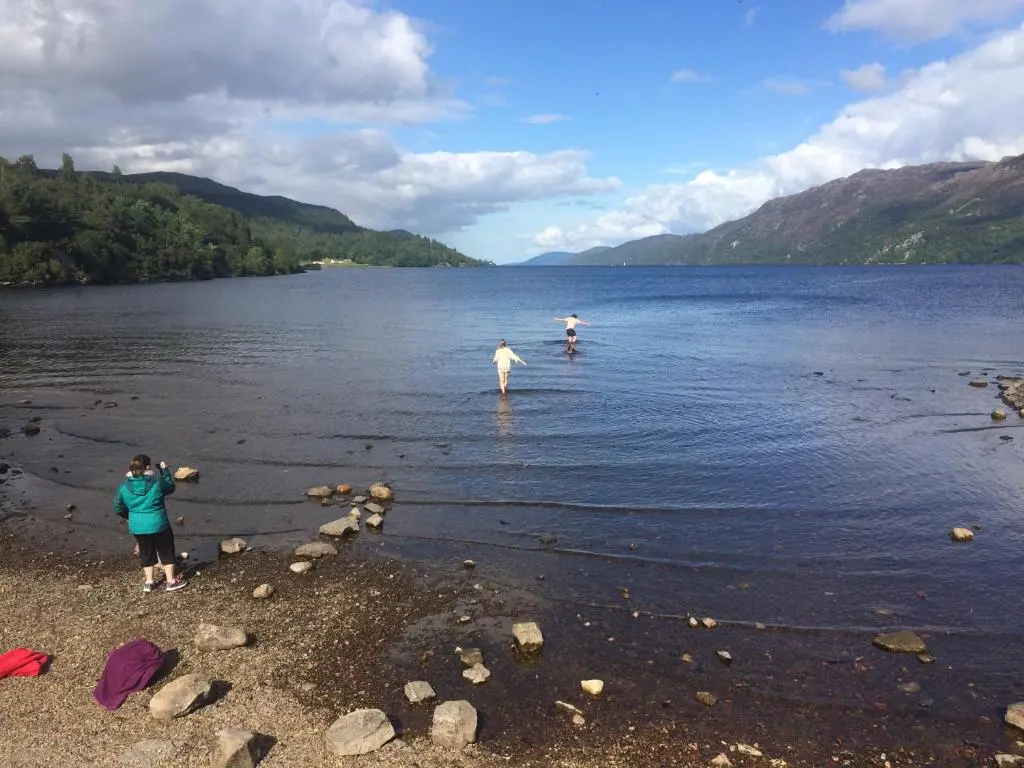 two people are standing in the water on a lake at The Wee Lodge in Inverness