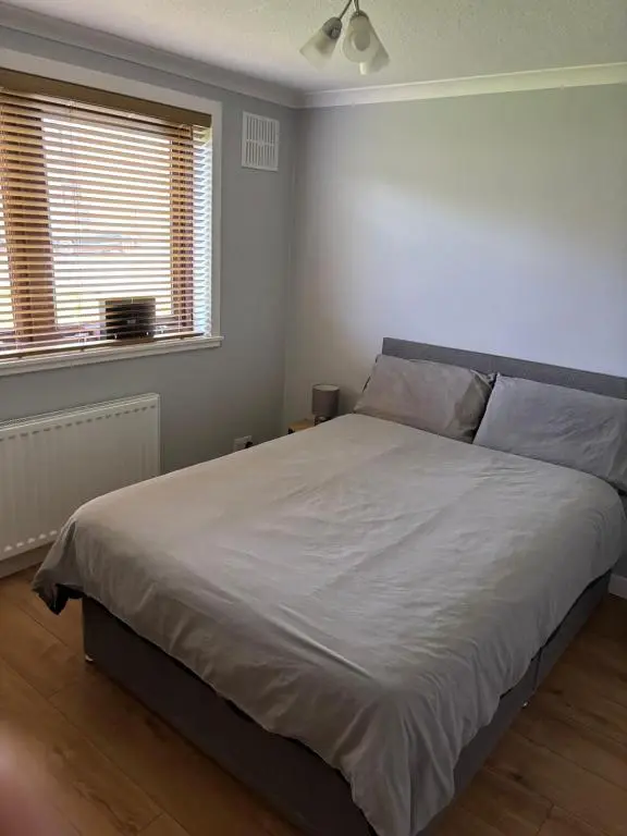 a bedroom with a large white bed with two windows at Wick Apartment in Wick