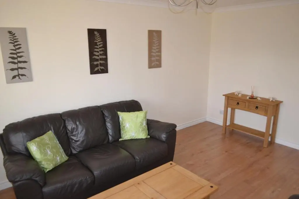 a black leather couch in a living room with a table at Wick Apartment in Wick