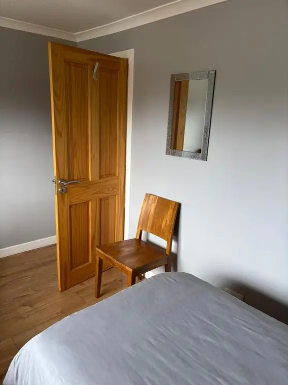 a bedroom with a bed and a chair and a door at Wick Apartment in Wick