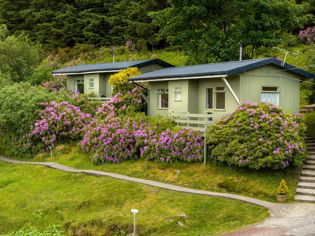 a house with flowers in front of it at Loch Broom Cabins Seaviews& Petfriendly in Leckmelm