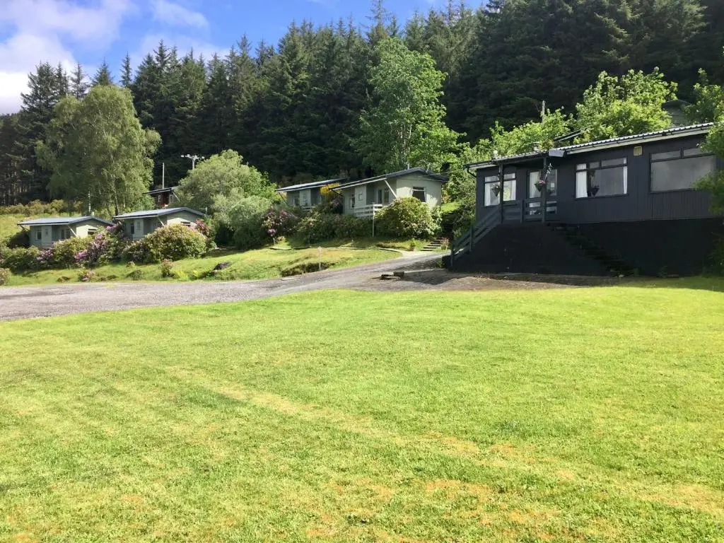 a house with a green lawn in front of it at Loch Broom Cabins Seaviews& Petfriendly in Leckmelm