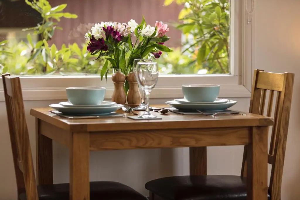 a wooden table with two bowls and a vase of flowers at Loch Broom Cabins Seaviews& Petfriendly in Leckmelm