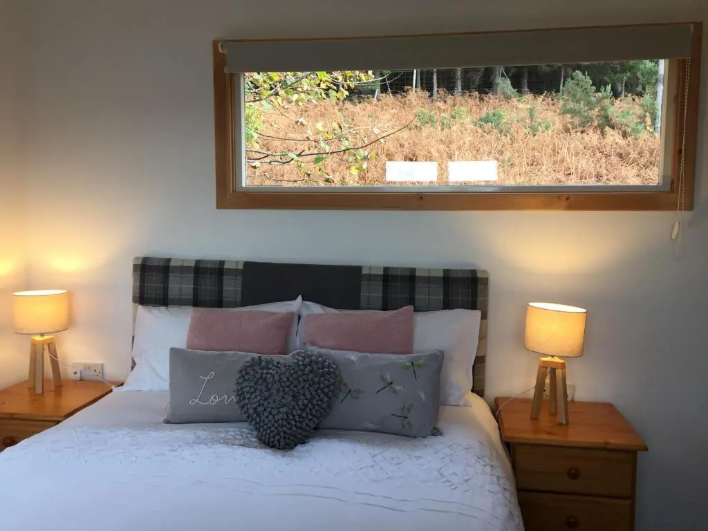a bedroom with a bed with two lamps and a window at Loch Broom Cabins Seaviews& Petfriendly in Leckmelm