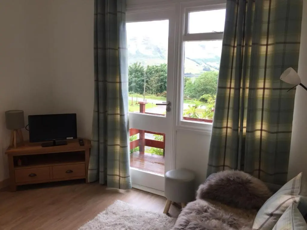 a living room with a window and a television at Loch Broom Cabins Seaviews& Petfriendly in Leckmelm