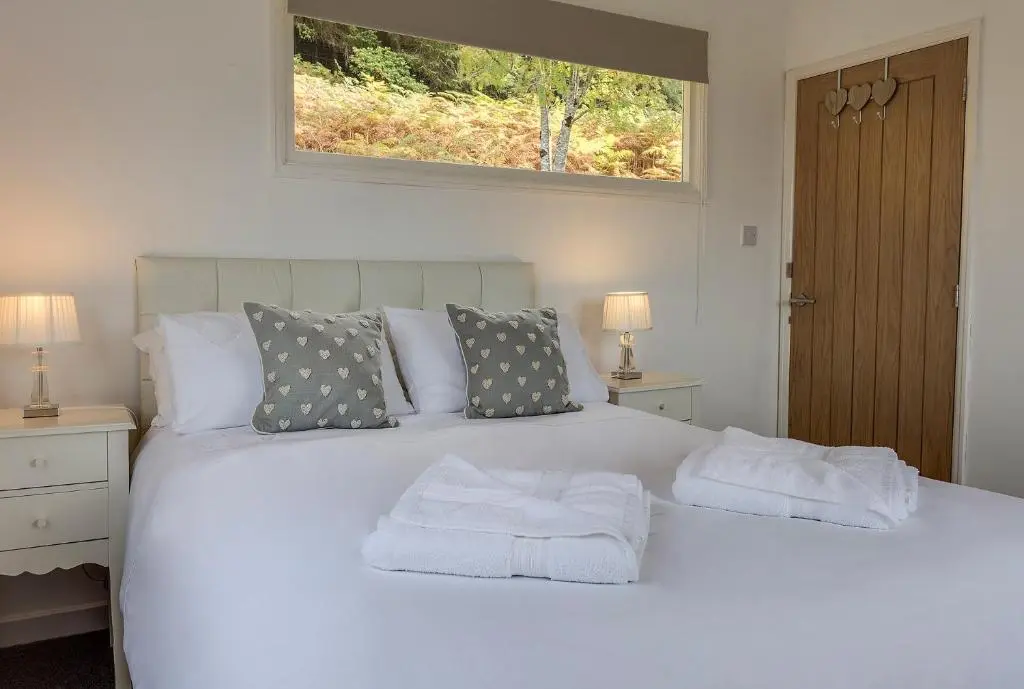 a bedroom with a white bed with towels on it at Loch Broom Cabins Seaviews& Petfriendly in Leckmelm