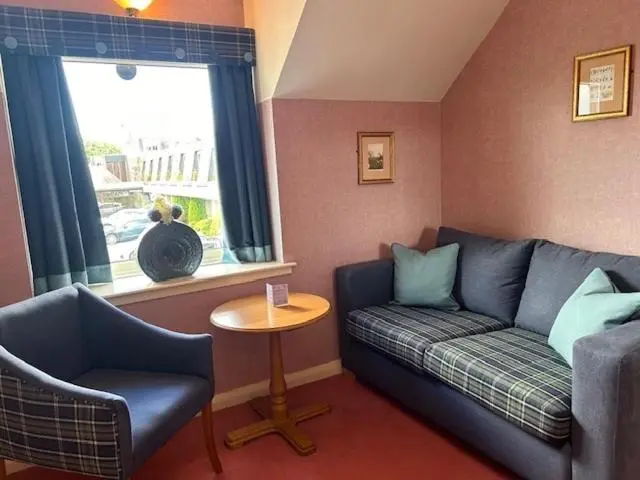 a living room with a couch and a table and a window at The Craighaar Hotel in Aberdeen