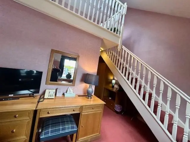 a room with a staircase and a desk with a television at The Craighaar Hotel in Aberdeen