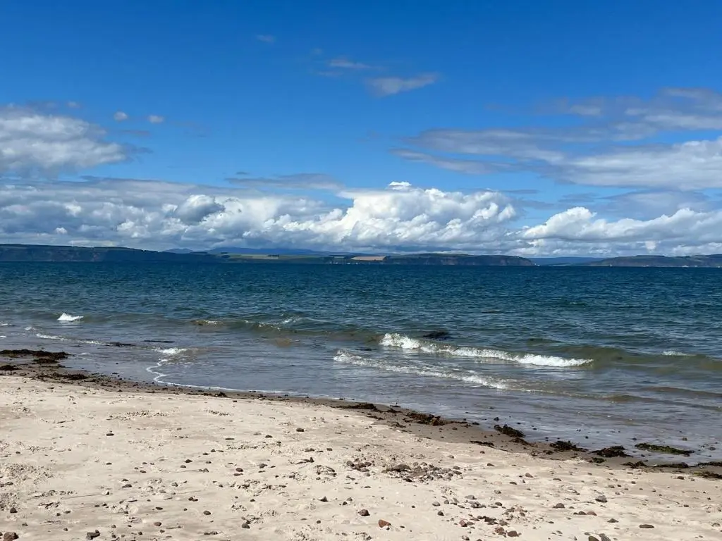 a sandy beach with waves in the ocean at Sunny Brae Bed & Breakfast in Nairn
