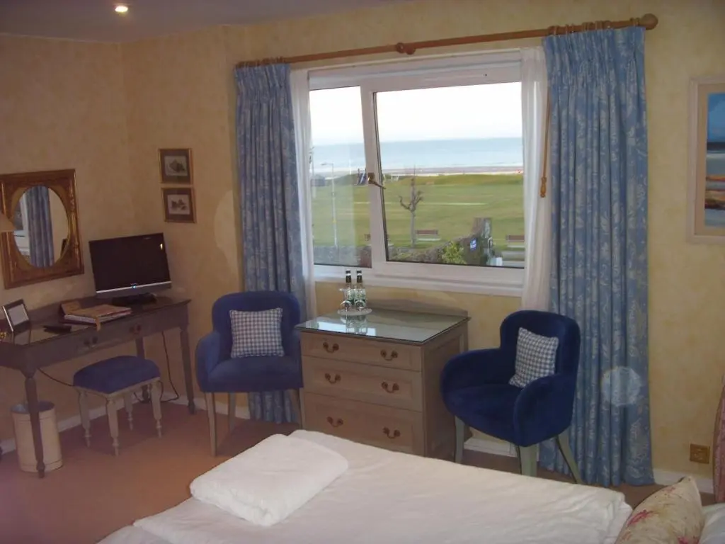 a bedroom with a bed and a desk and a window at Sunny Brae Bed & Breakfast in Nairn