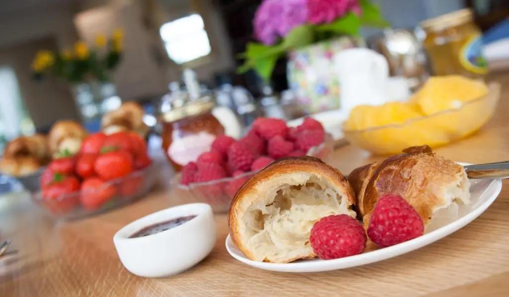 a plate with bread and raspberries and fruit on a table at Sunny Brae Bed & Breakfast in Nairn
