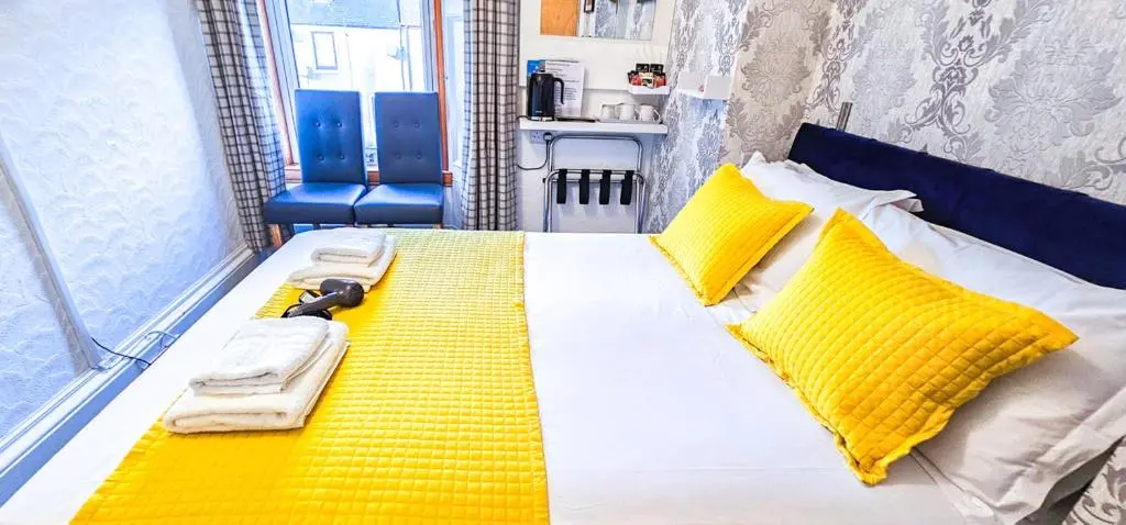 a bedroom with a bed with yellow pillows and a yellow blanket at mySTAYINN Kinloch Lodge in Inverness