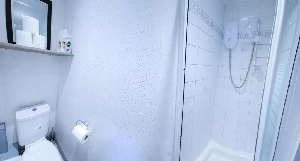 a white bathroom with a shower and a toilet at mySTAYINN Kinloch Lodge in Inverness
