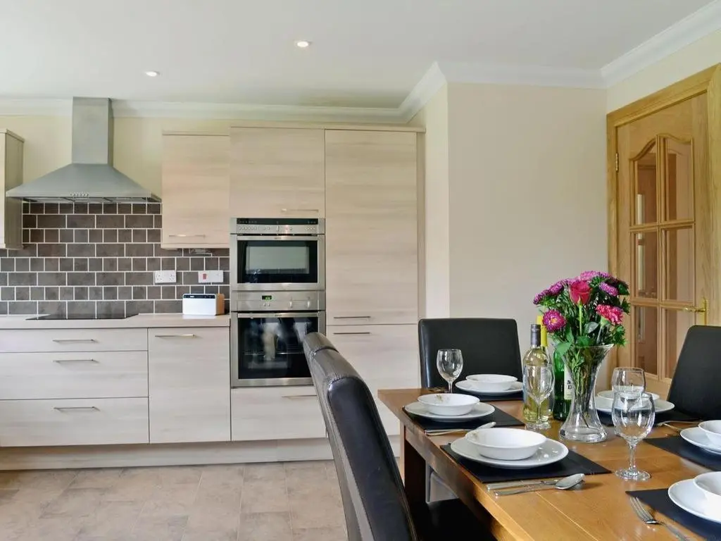 a kitchen with a wooden table and a dining room at Woodlands in Aviemore