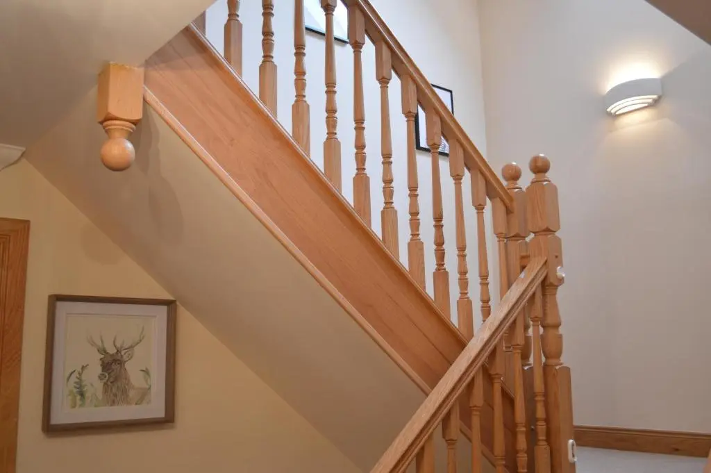 a staircase with wooden railings and a painting on the wall at Woodlands in Aviemore