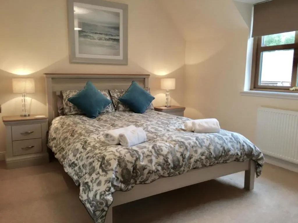 a bedroom with a bed with two towels on it at Woodlands in Aviemore
