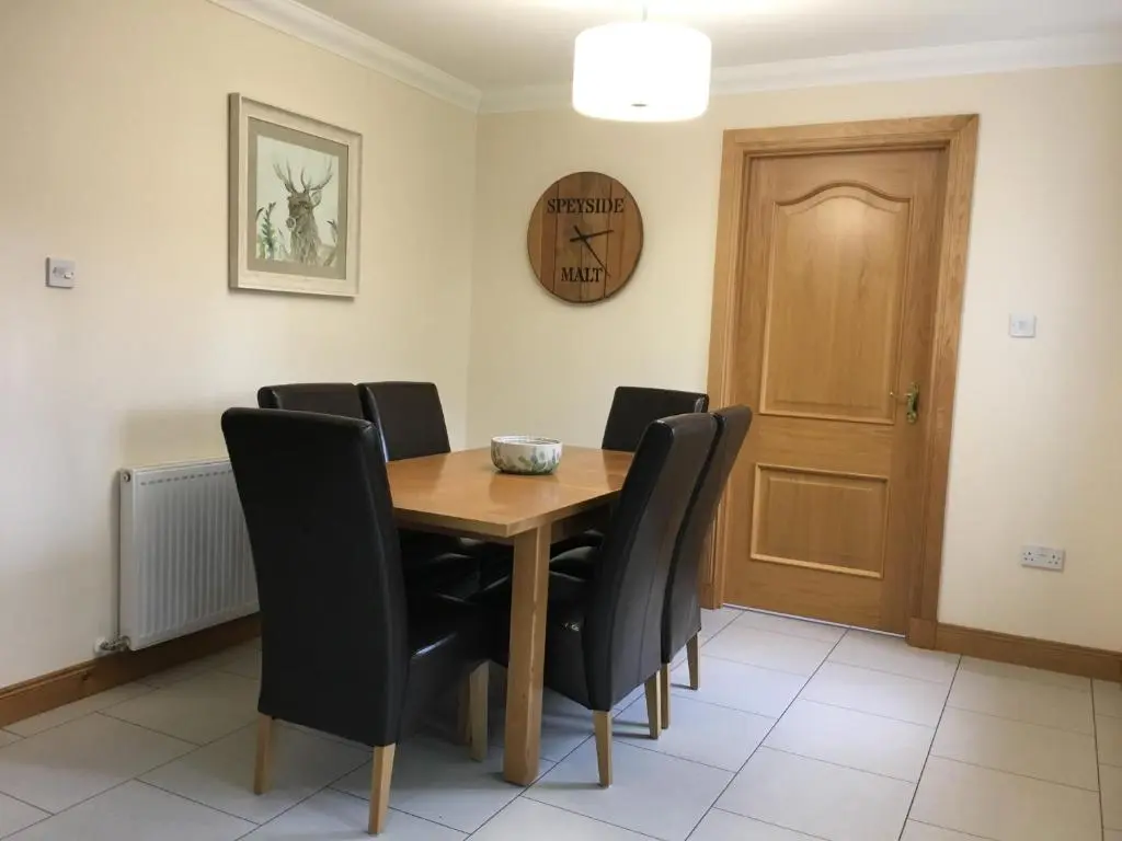 a dining room with a wooden table and black chairs at Woodlands in Aviemore