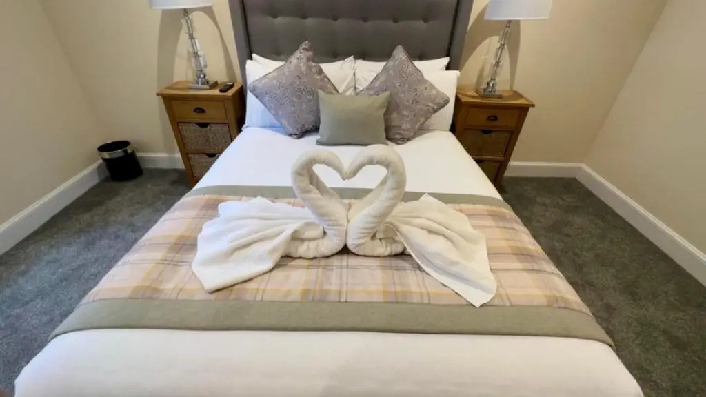 two towels in the shape of a heart on a bed at The Waverley Inn Holiday Homes in Inverness