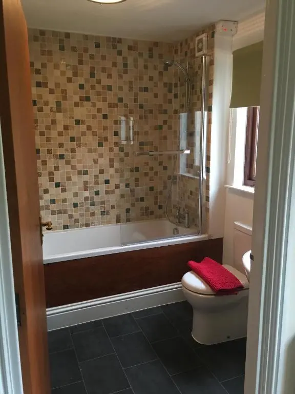 a bathroom with a tub and a toilet and a shower at The Ship Inn in Invergordon