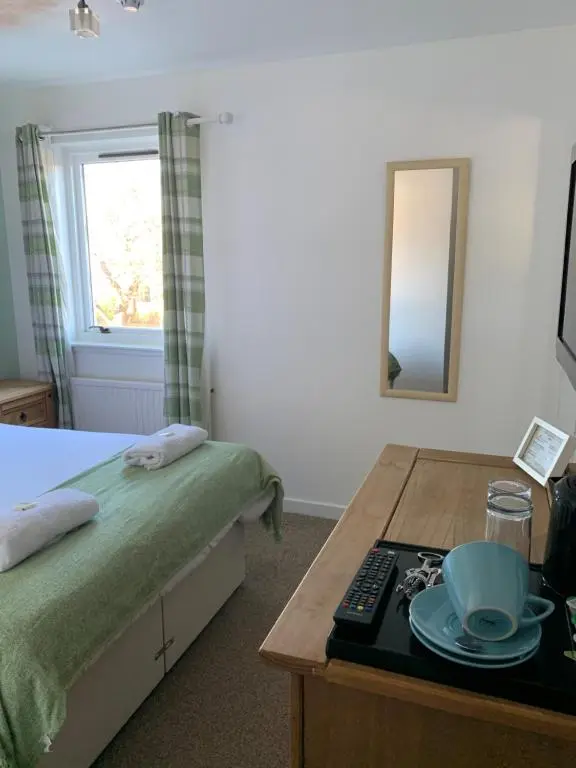 a bedroom with a bed and a table and a mirror at The Ship Inn in Invergordon
