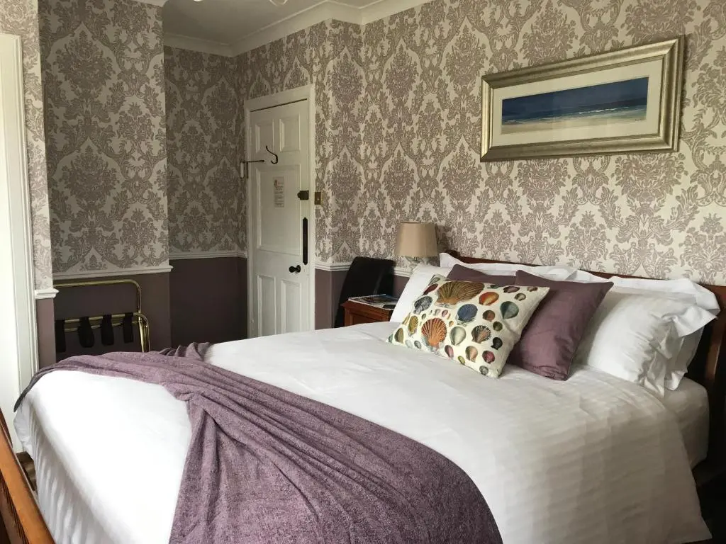 a bedroom with a large white bed and wallpaper at Dalgreine Guest House in Blair Atholl