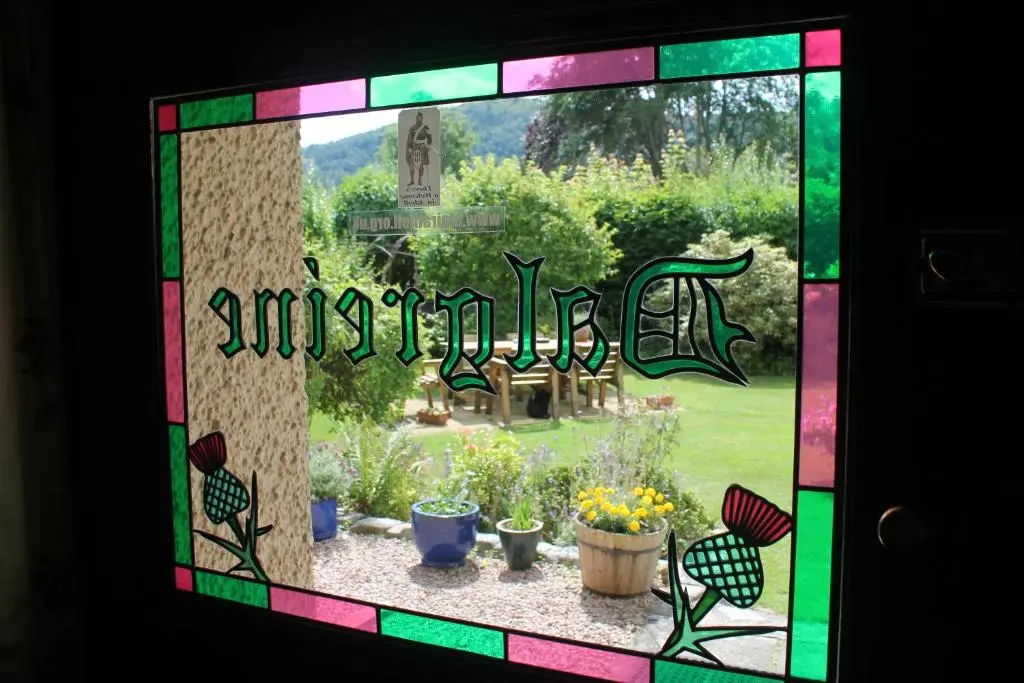 a stained glass window of a garden with potted plants at Dalgreine Guest House in Blair Atholl