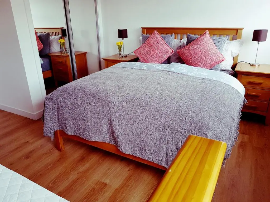 a bedroom with a large bed with pink pillows at Yvi's 2Bedroom 2Bathroom Apartment in Inverurie