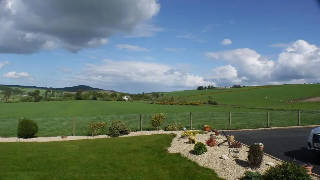 a yard with a fence and a grassy field at Hillhaven Bed &Breakfast in Fortrose