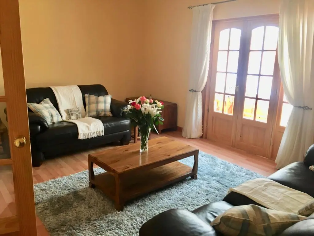 a living room with a vase of flowers on a coffee table at White Cottage B&B in North Kessock