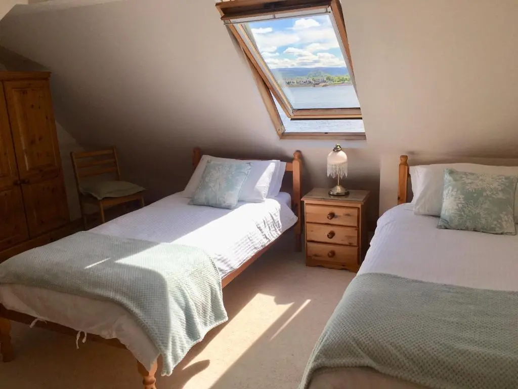 a attic bedroom with two beds and a window at White Cottage B&B in North Kessock