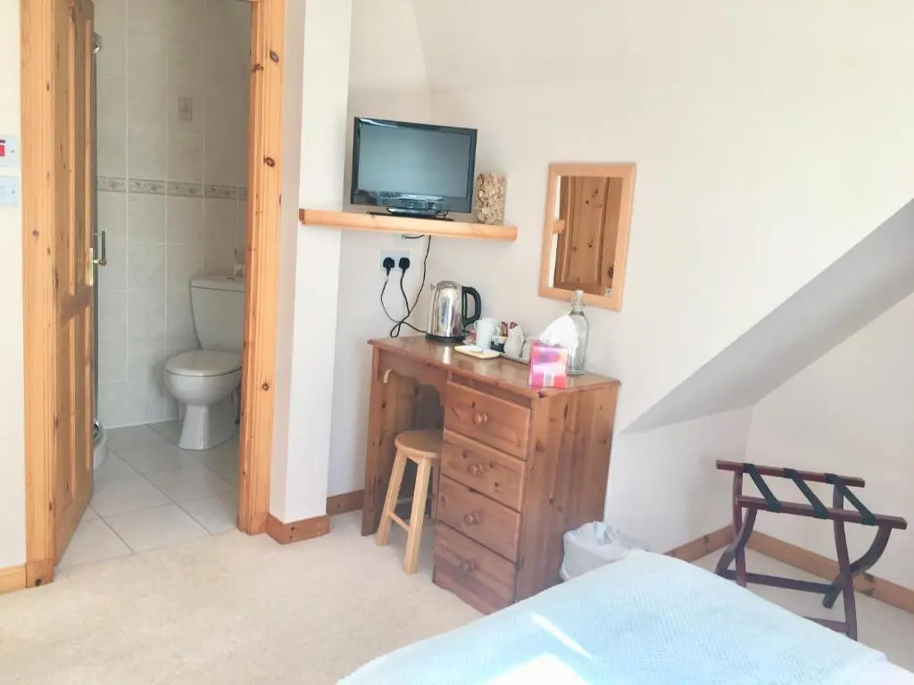 a room with a bathroom with a toilet and a television at White Cottage B&B in North Kessock