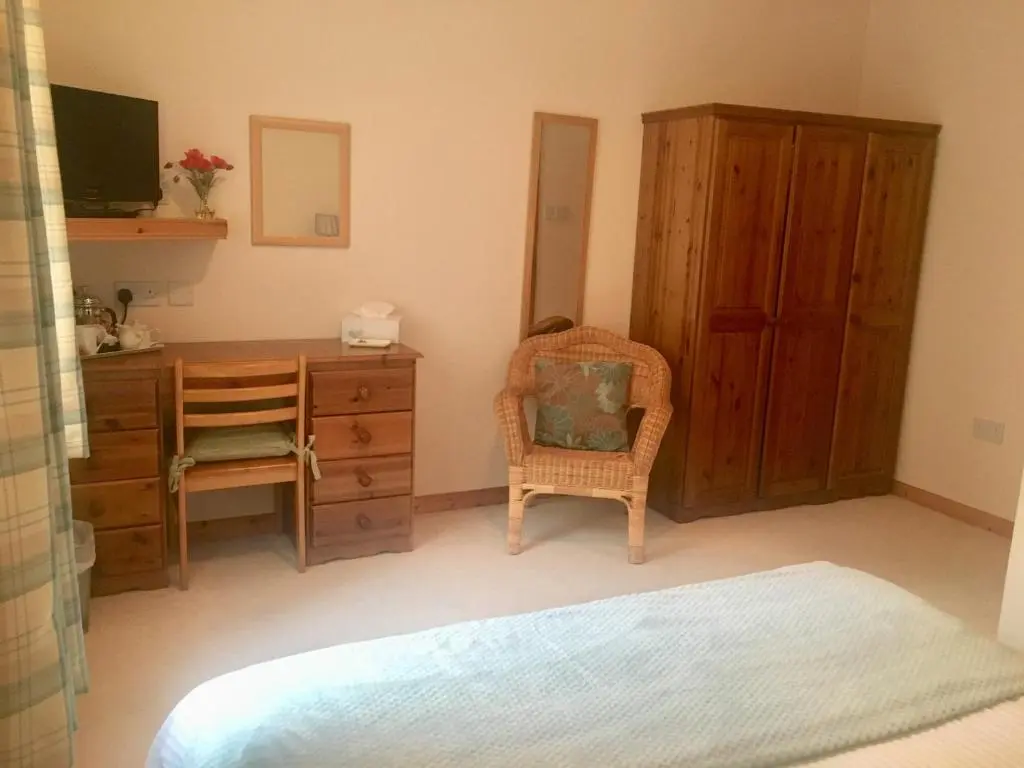 a bedroom with a desk and a chair and a dresser at White Cottage B&B in North Kessock