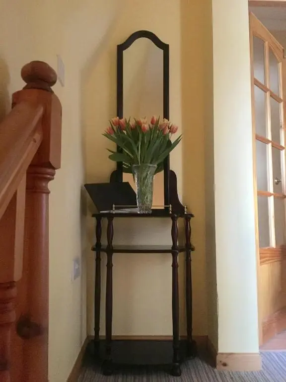 a vase of flowers on a table with a mirror at White Cottage B&B in North Kessock