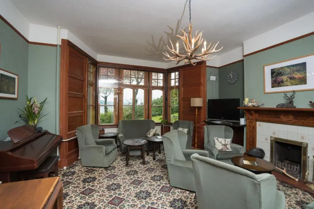 a living room with a table and chairs and a fireplace at Foyers Bay Country House in Foyers