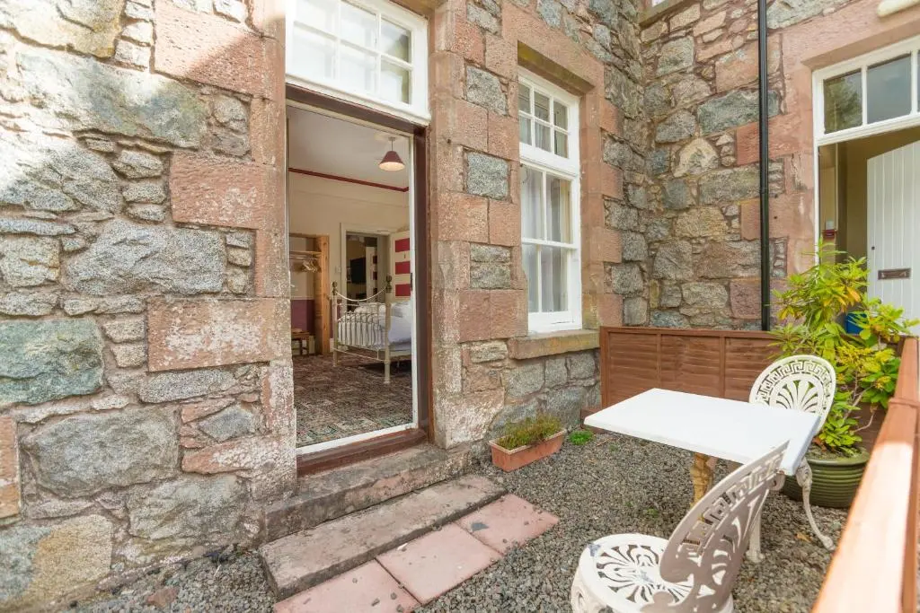 a stone house with a table and chairs on a patio at Foyers Bay Country House in Foyers