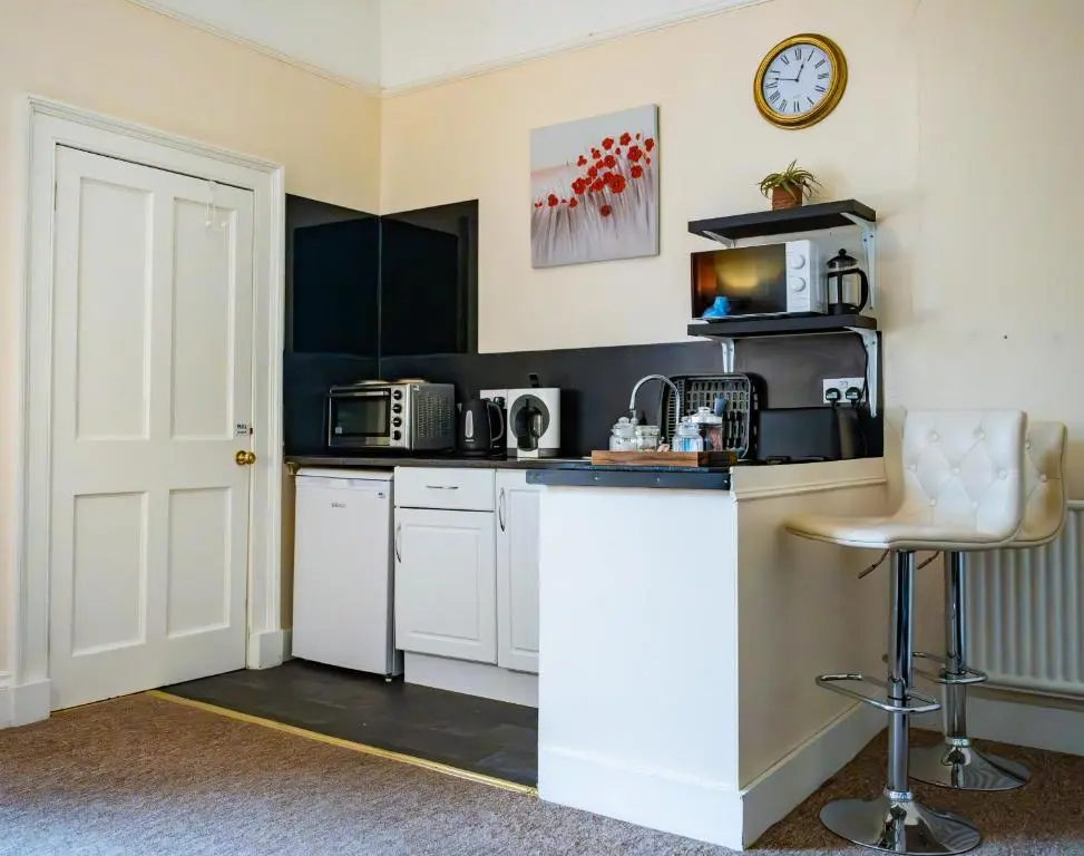 a kitchen with white cabinets and a clock on the wall at East Wing Apartment in Elgin in Elgin