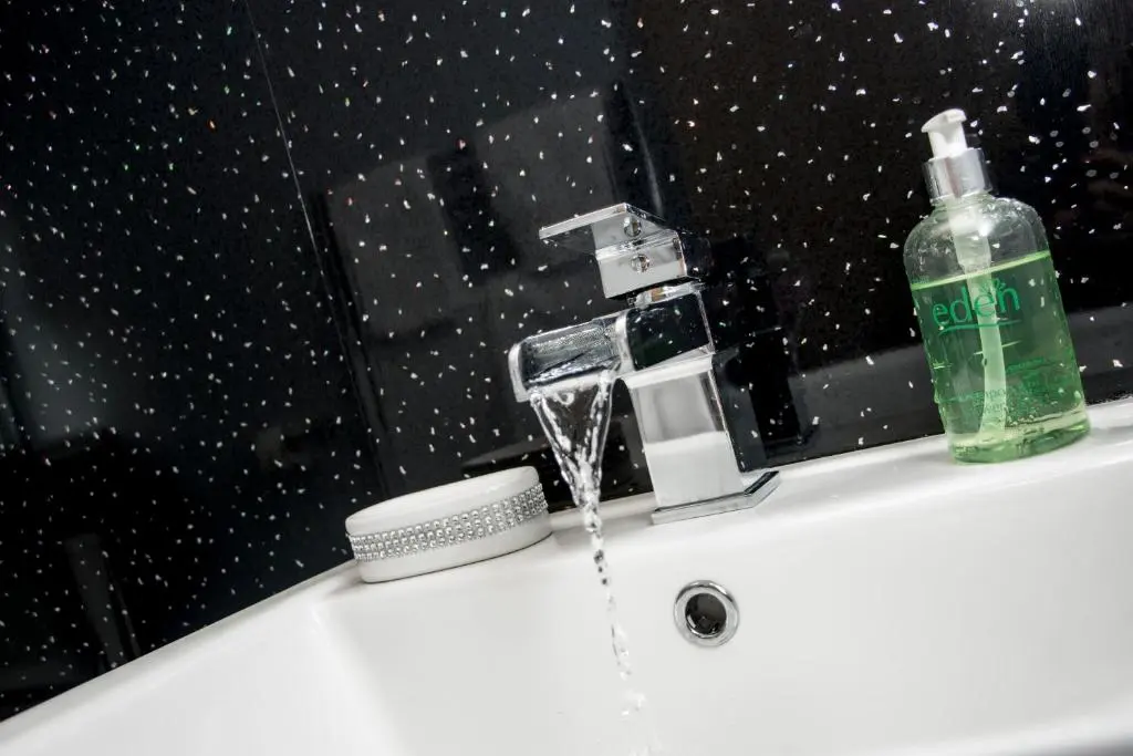 a sink with a faucet and a bottle of water at Distillery Apartment 1 in Elgin