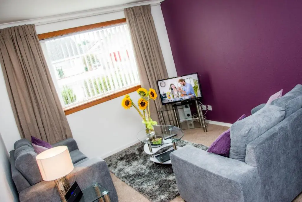 a purple living room with two chairs and a window at Distillery Apartment 1 in Elgin