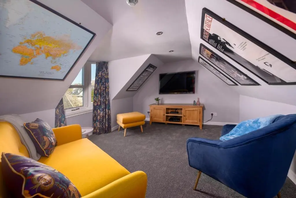 a living room with a yellow couch and a tv at Dryburgh Town House in Inverness