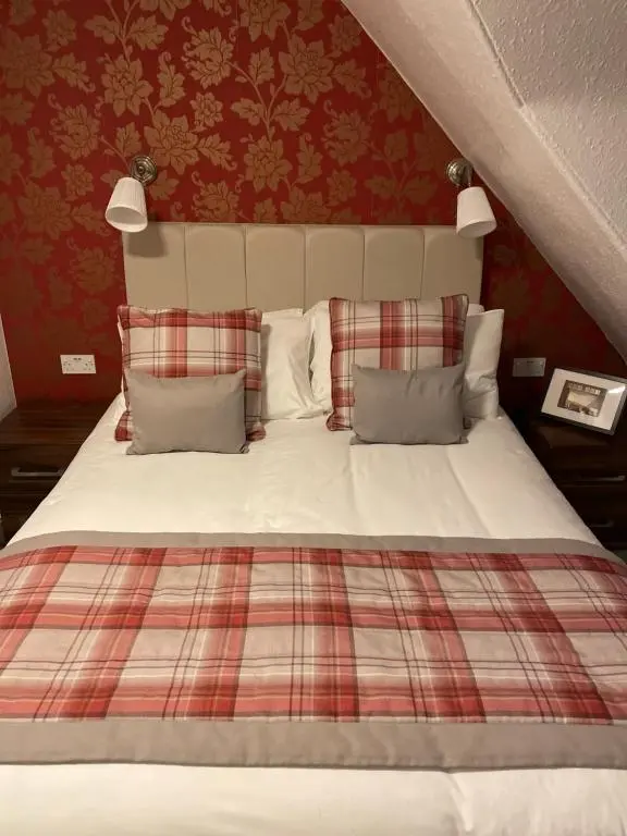 a bed with a plaid blanket and pillows at Royston Guest House Inverness in Inverness