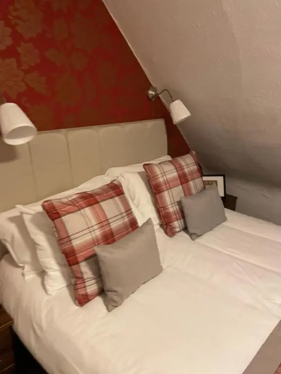 a white bed with two pillows on top of it at Royston Guest House Inverness in Inverness